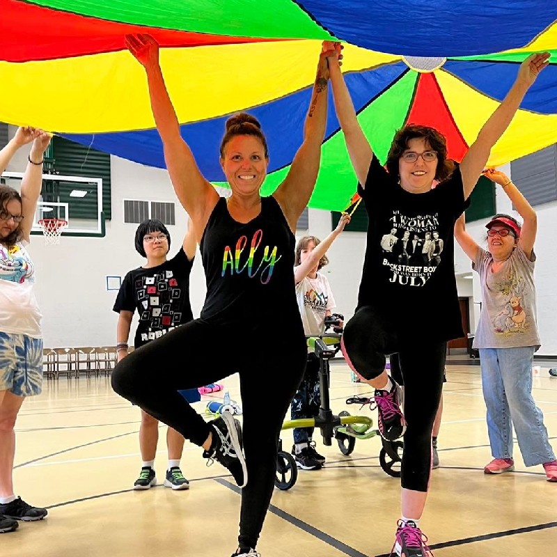 Angela Siciliano during adapted fitness & yoga class in tree pose with hands in the air